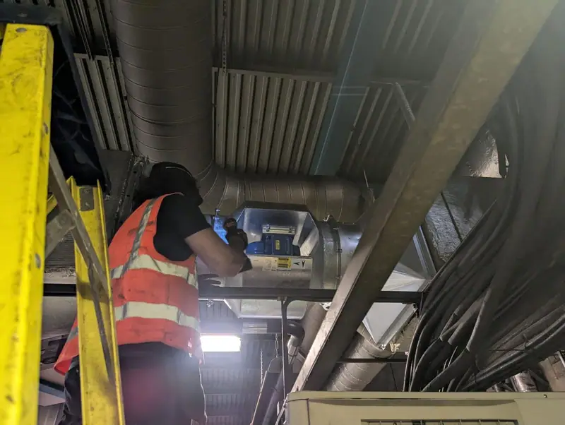 Engineer servicing equipment in a ceiling void