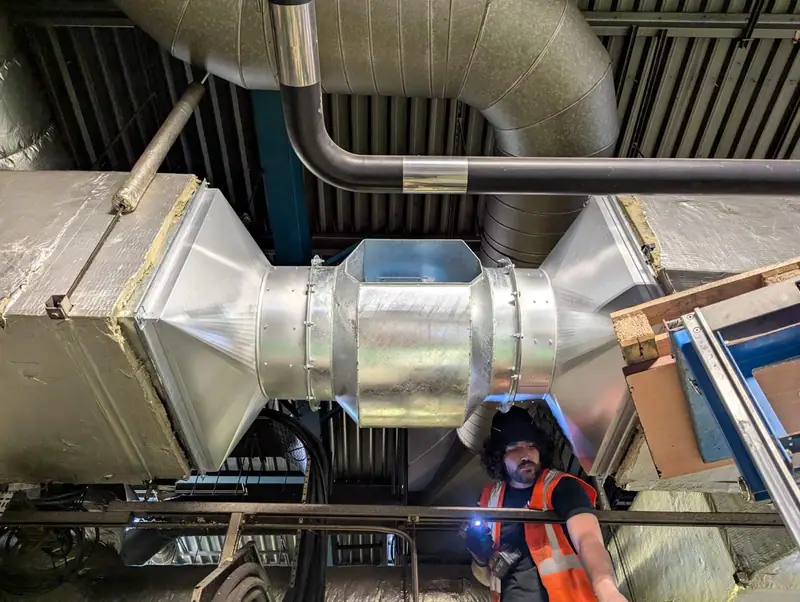First HVAC engineer working on galvanised ductwork beneath a roof deck