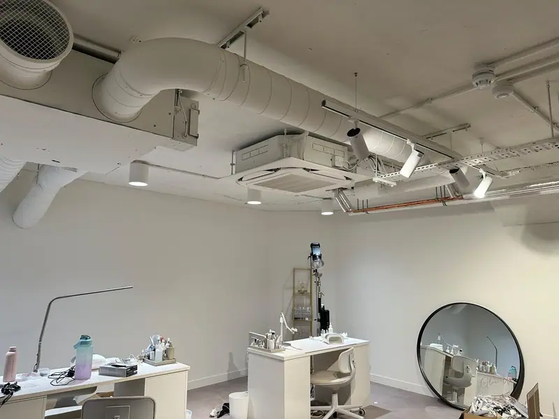 Exposed ceiling with cassette and spiral ductwork above training desks